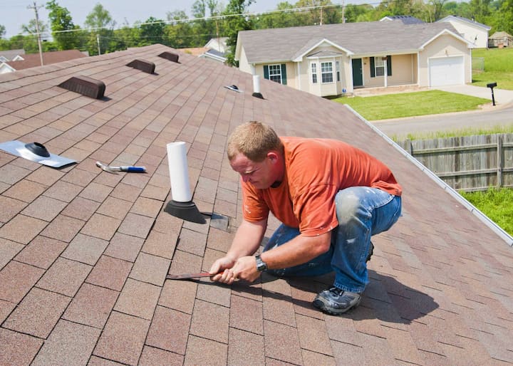 A professional technician begins fixing shingles during roof maintenance on a Peoria, IL home's roof.